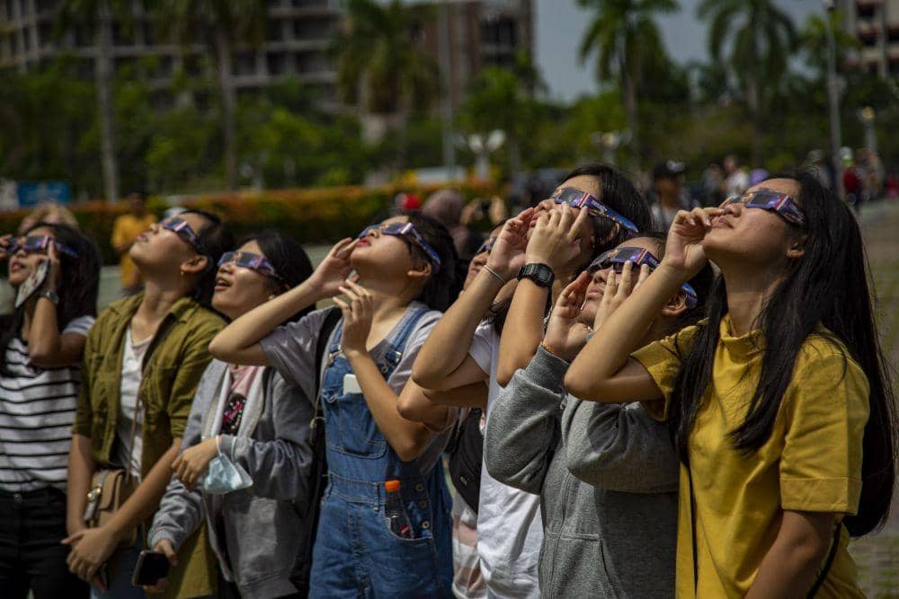 Wisatawan melihat gerhana matahari cincin dengan menggunakan kacamata solar di Batam, Kepulauan Riau. ANTARA FOTO/M N Kanwa