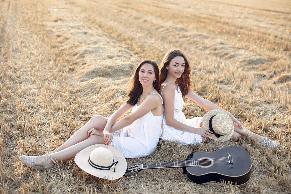 dua perempuan duduk di padang rumput