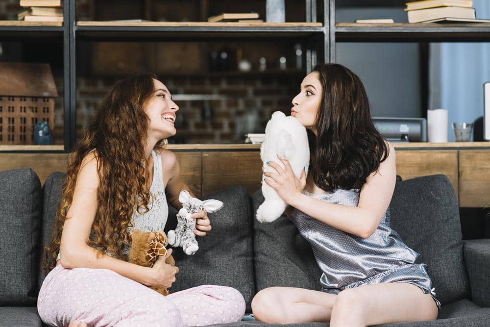 two-young-women-sitting-sofa-holding-soft-toy.jpg