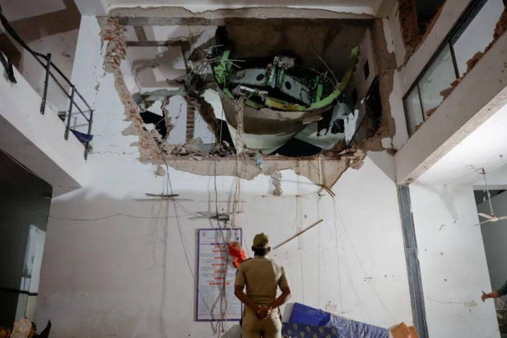 Seorang petugas polisi berdiri di depan puing-puing tempat terjadinya kecelakaan pesawat Air India AI171 di Ahmedabad (Dok. Reuters)