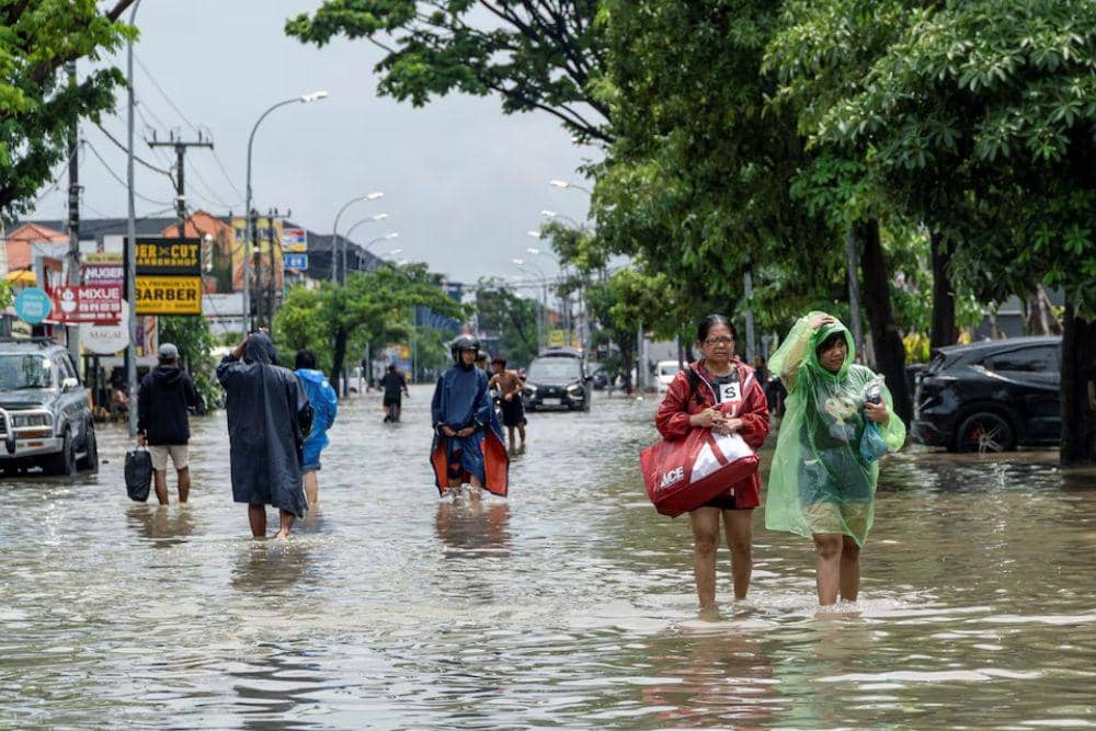 Warga membawa barang-barang mereka sambil menerjang banjir di kawasan Legian, Badung, Bali, usai hujan deras semalam, Rabu (10/9/2025). (REUTERS/Dicky Bisinglasi)