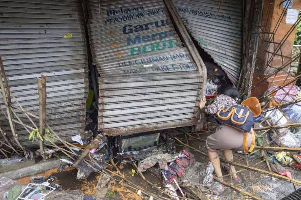 Salah satu bangunan terdampak banjir dengan pagar dan garasi rusak serta menyisakan lumpur, sementara sejumlah barang tampak terseret dan berserakan. (EPA/Made Nagi via sbs.com.au)