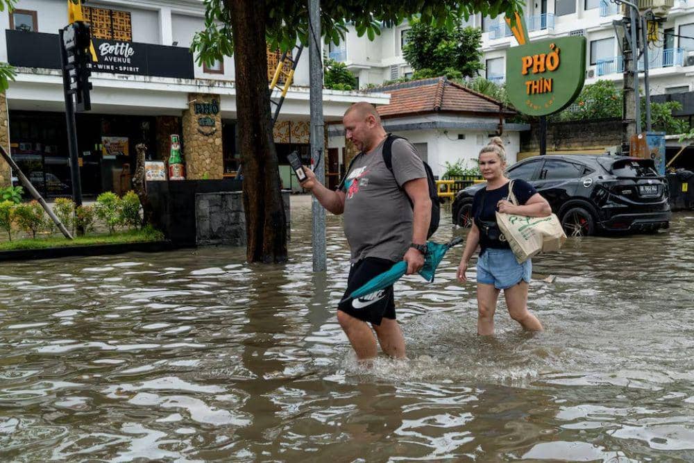 Sejumlah turis berjalan menerjang banjir di jalanan Legian, Badung, Bali, usai diguyur hujan deras semalam, Rabu (10/9/2025). (REUTERS/Dicky Bisinglasi)