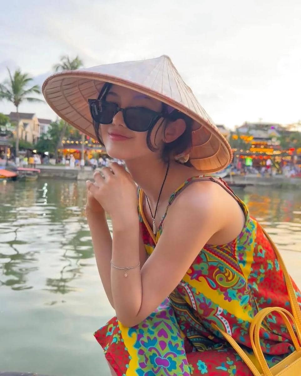 Danielle memakai dress motif warna warni dengan kacamata hitam dan topi tradisional khas Vietnam