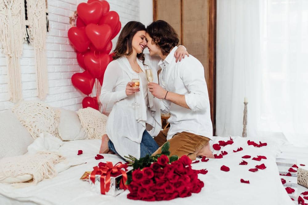 cheerful-couple-sitting-bed-face-face-with-champagne-glasses-celebrating-st-valentines-day-together.jpg