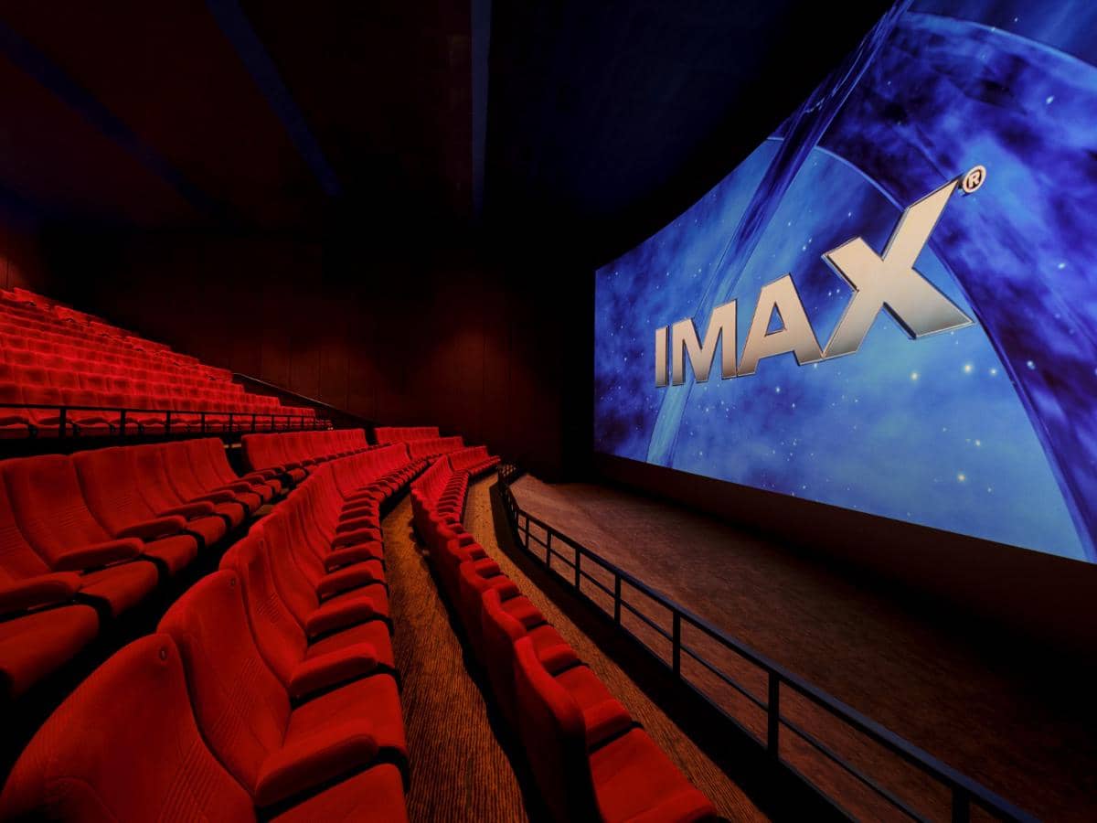 Ruang teater IMAX dengan deretan kursi merah dan layar besar menampilkan logo IMAX di dalam bioskop modern.