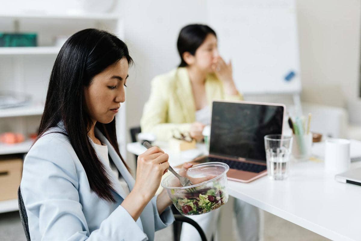 wanita makan salad di kantor.