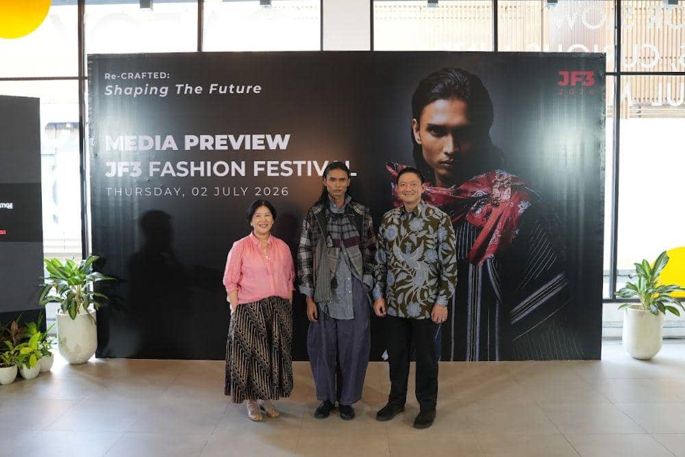 Tiga orang berpose di depan backdrop bertuliskan Media Preview JF3 Fashion Festival 2026 dengan tema Re-Crafted: Shaping The Future.