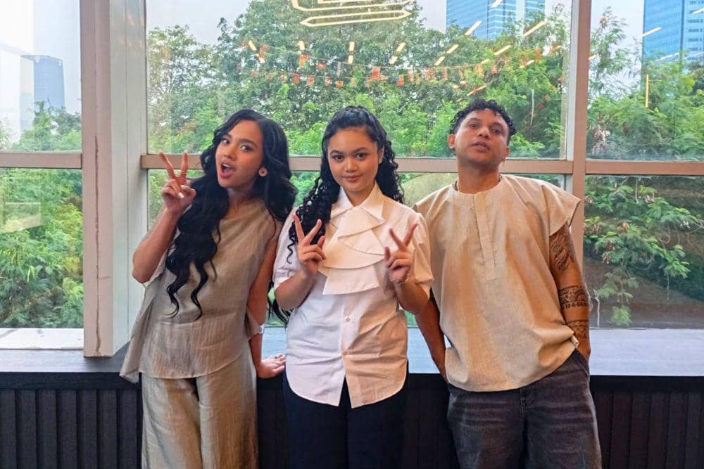 Lyodra, Amora Lemos, dan Silet Open Up berpose bersama di depan jendela besar dengan latar pepohonan dan gedung perkotaan.