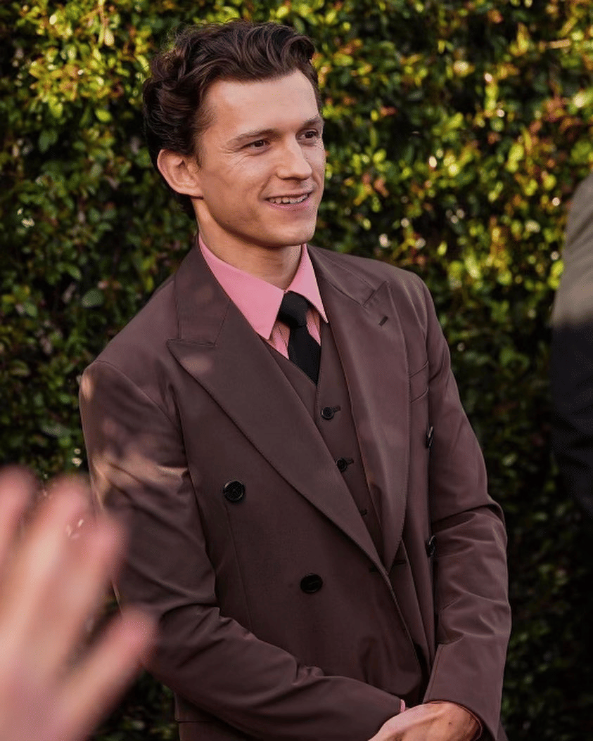 Tom Holland mengenakan setelan jas cokelat dengan kemeja merah muda dan dasi hitam saat menghadiri acara Critics Choice Awards ke-29.