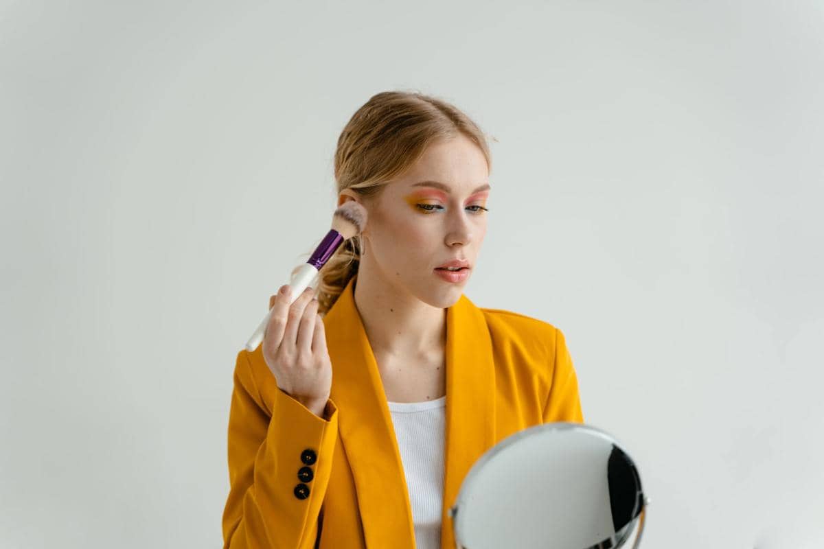 seorang wanita menggunakan blush on di wajah