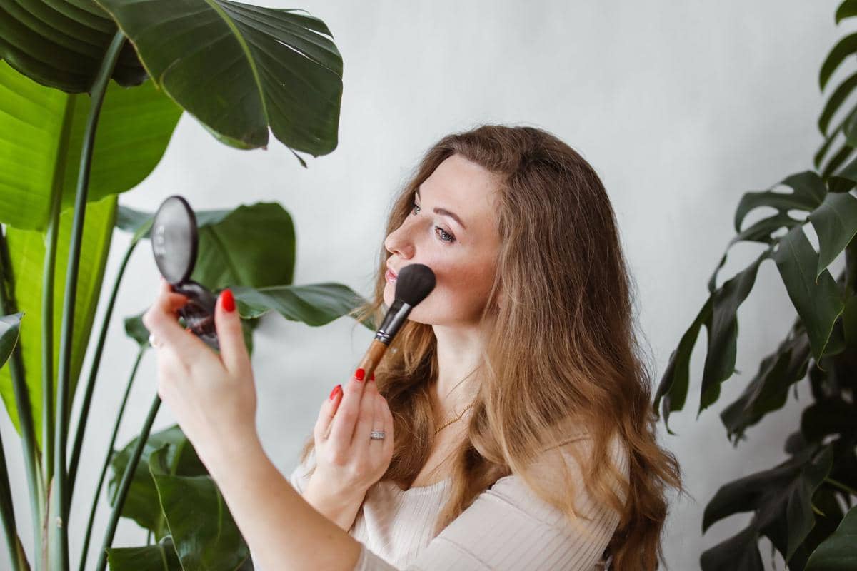 seorang wanita menggunakan blush on di wajah