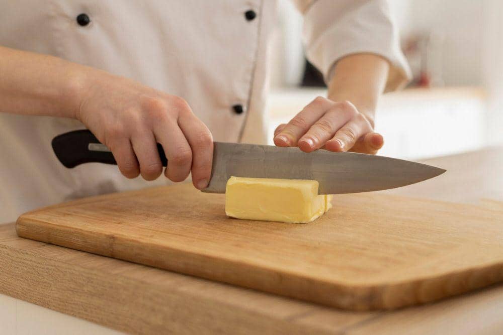 Ilustrasi proses memotong butter menjadi beberapa bagian kecil sebagai persiapan memasak dan membuat kue.
