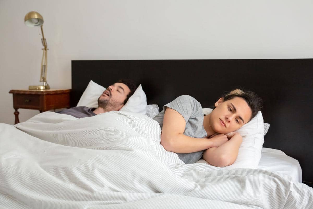 Pasangan tidur di tempat tidur sebagai ilustrasi mendengkur saat malam hari.